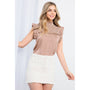 Woman wearing a brown textured top and white skirt on a white background