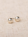 Pair of silver round earrings on a beige fabric background