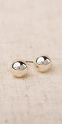 Pair of silver round earrings on a beige fabric background