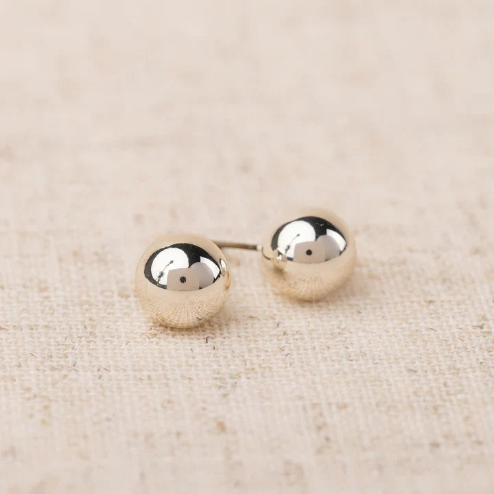 Pair of silver round earrings on a beige fabric background
