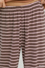 Close-up of a person wearing striped lounge pants in mauve and light pink, with the waistband and hands visible at the top.
