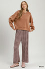 A woman modeling a two-piece lounge set consisting of a cropped mauve sweatshirt and matching wide-leg pants with thin brown stripes, paired with pink sneakers, on a light gray studio background.