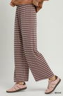 A person wearing loose, wide-leg striped pants in mauve and brown, paired with pink sneakers, shown against a plain light gray studio background. The word 'MAUVE' appears in the lower right corner.