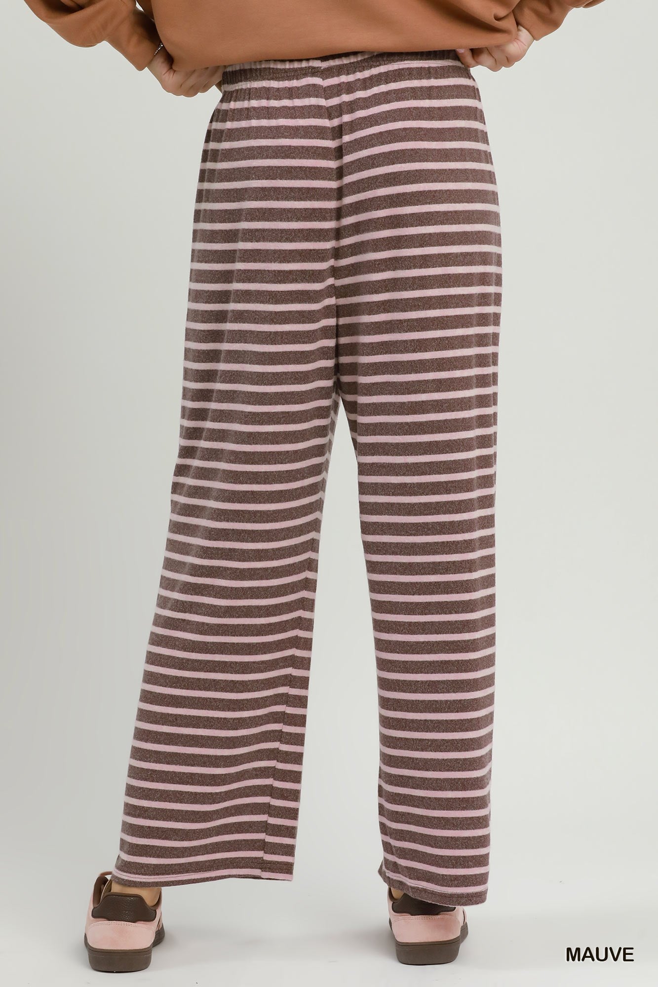 A person shown from the back wearing loose, wide-leg striped pants in mauve and beige, with a tan top and pink shoes against a light gray studio background. The word 'MAUVE' appears in the bottom right corner.