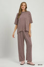 A woman modeling a matching two-piece loungewear set consisting of a short-sleeve crewneck top and wide-leg pants, both in a brown and white horizontal stripe pattern. She is wearing mauve-colored slip-on shoes.