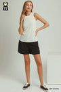 A woman modeling a sleeveless off-white tank top and black athletic shorts, standing in a studio setting with a white block prop and text reading 'OFF WHITE' in the corner.