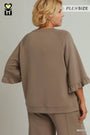 A woman shown from the back wearing a taupe-brown lounge set with wide three-quarter sleeves and ruffled cuffs, photographed against a plain light gray studio background. Text overlays read PLUS SIZE and MOCHA.