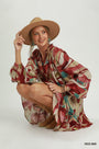 A woman crouches in a studio wearing a loose, long-sleeve bohemian-style dress with an abstract red, beige, and teal print, along with a wide-brim tan hat. The text 'RED MIX' is printed in the bottom right corner.