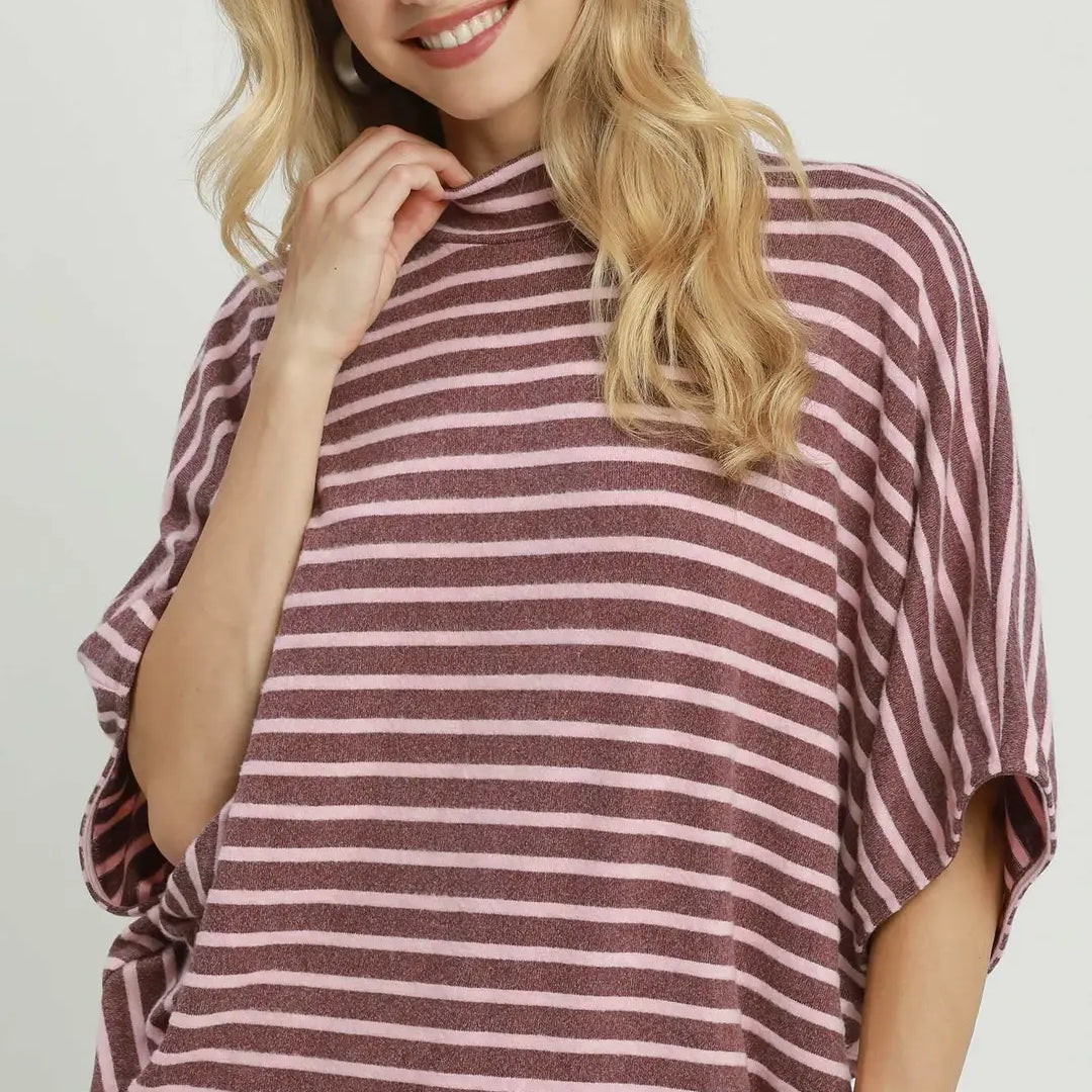 A woman wearing a mauve and white striped turtleneck top with wide batwing sleeves, shown against a light gray studio background. The word 'MAUVE' appears in the bottom right corner.
