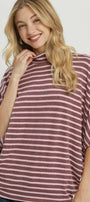 A woman wearing a mauve and white striped turtleneck top with wide batwing sleeves, shown against a light gray studio background. The word 'MAUVE' appears in the bottom right corner.