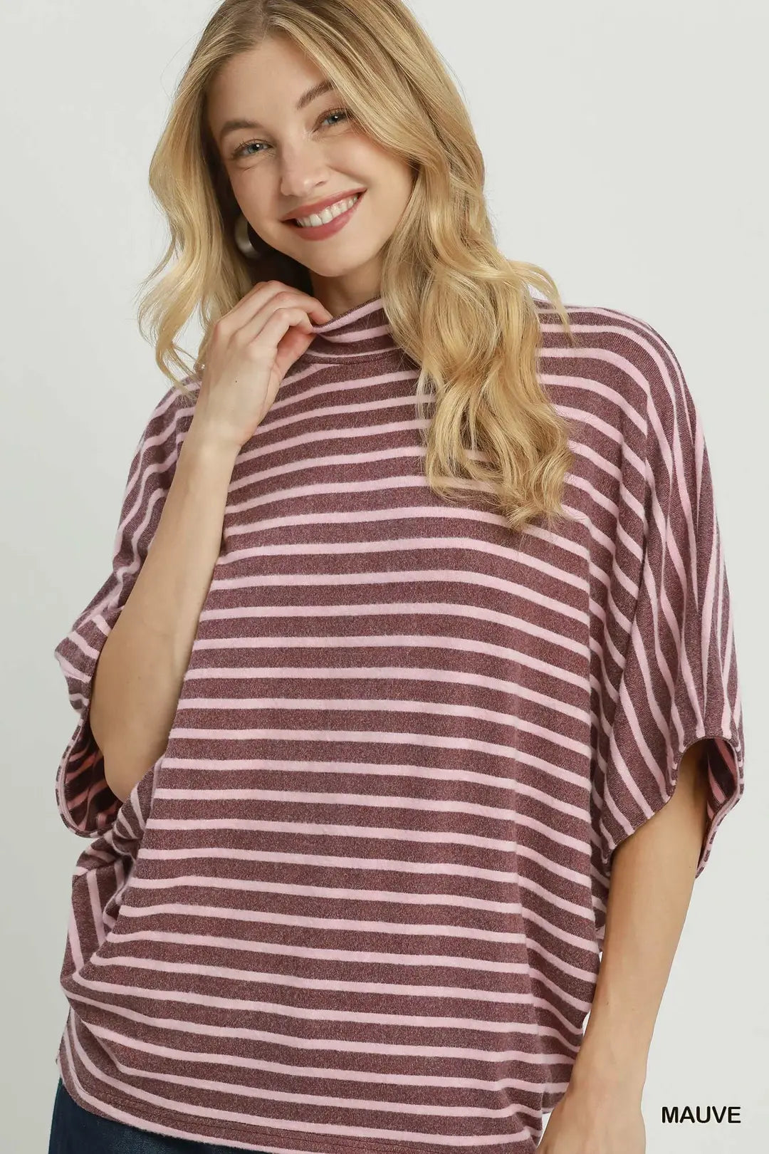 A woman wearing a mauve and white striped turtleneck top with wide batwing sleeves, shown against a light gray studio background. The word 'MAUVE' appears in the bottom right corner.