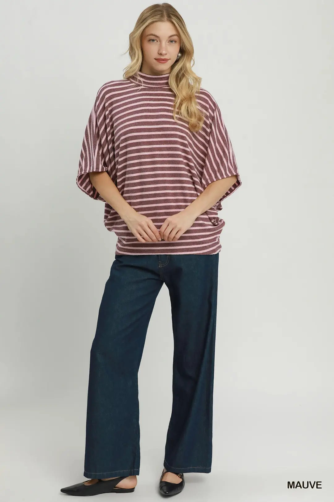 A woman modeling a mauve and white striped short-sleeve tunic top with dark blue wide-leg jeans, standing against a light gray studio background. The word 'MAUVE' appears in the bottom right corner.