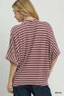 A woman shown from the back wearing a loose, short-sleeve striped top in mauve and white, paired with dark blue jeans, against a plain light gray studio background.