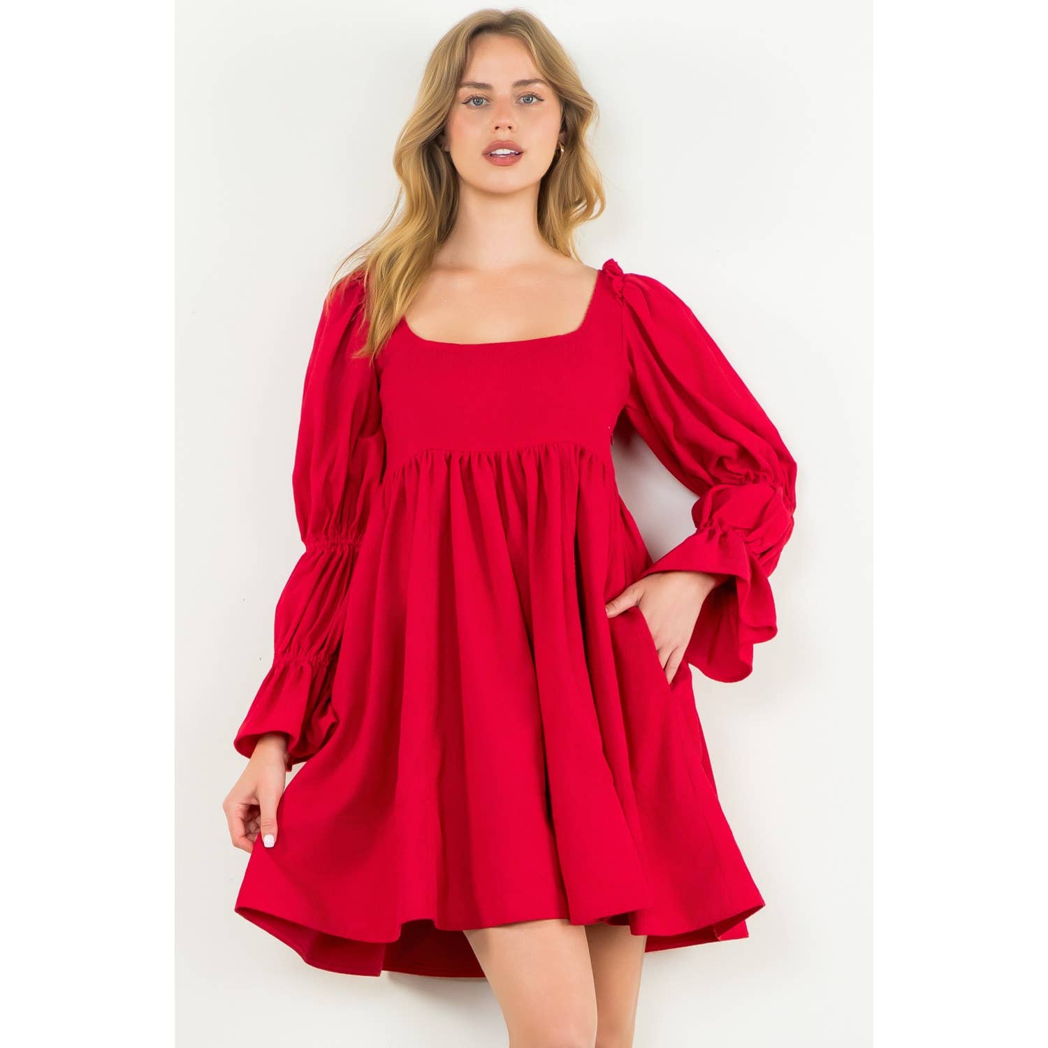 Woman wearing a red dress with puffed sleeves on a white background