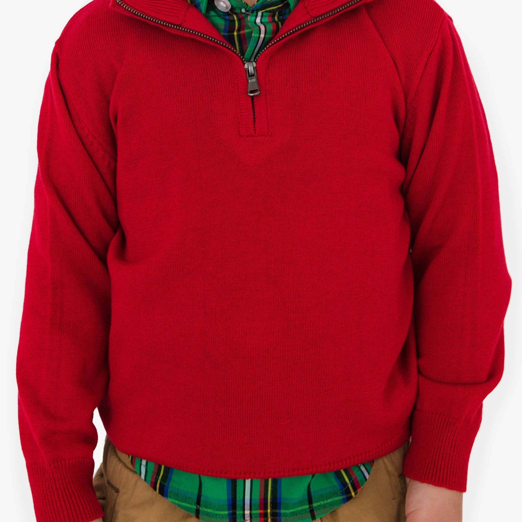 Child wearing a red sweater over a plaid shirt on a white background