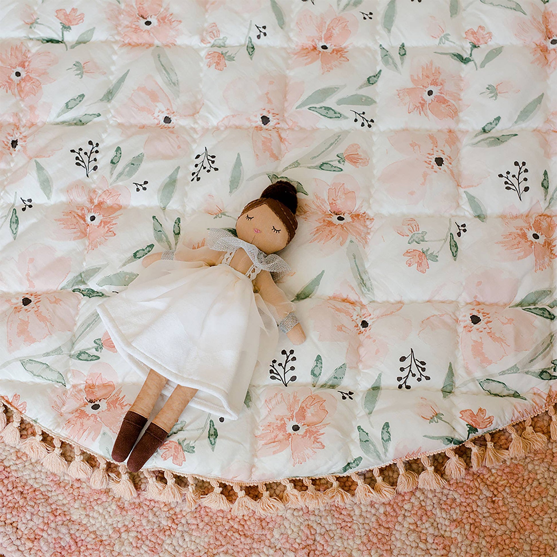 Doll lying on a floral-patterned quilt with a soft focus background