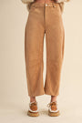 Tan suede pants worn by a person on a beige background