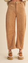 Tan suede pants worn by a person on a beige background