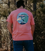 Person wearing a pink t-shirt with a graphic design in a forest setting