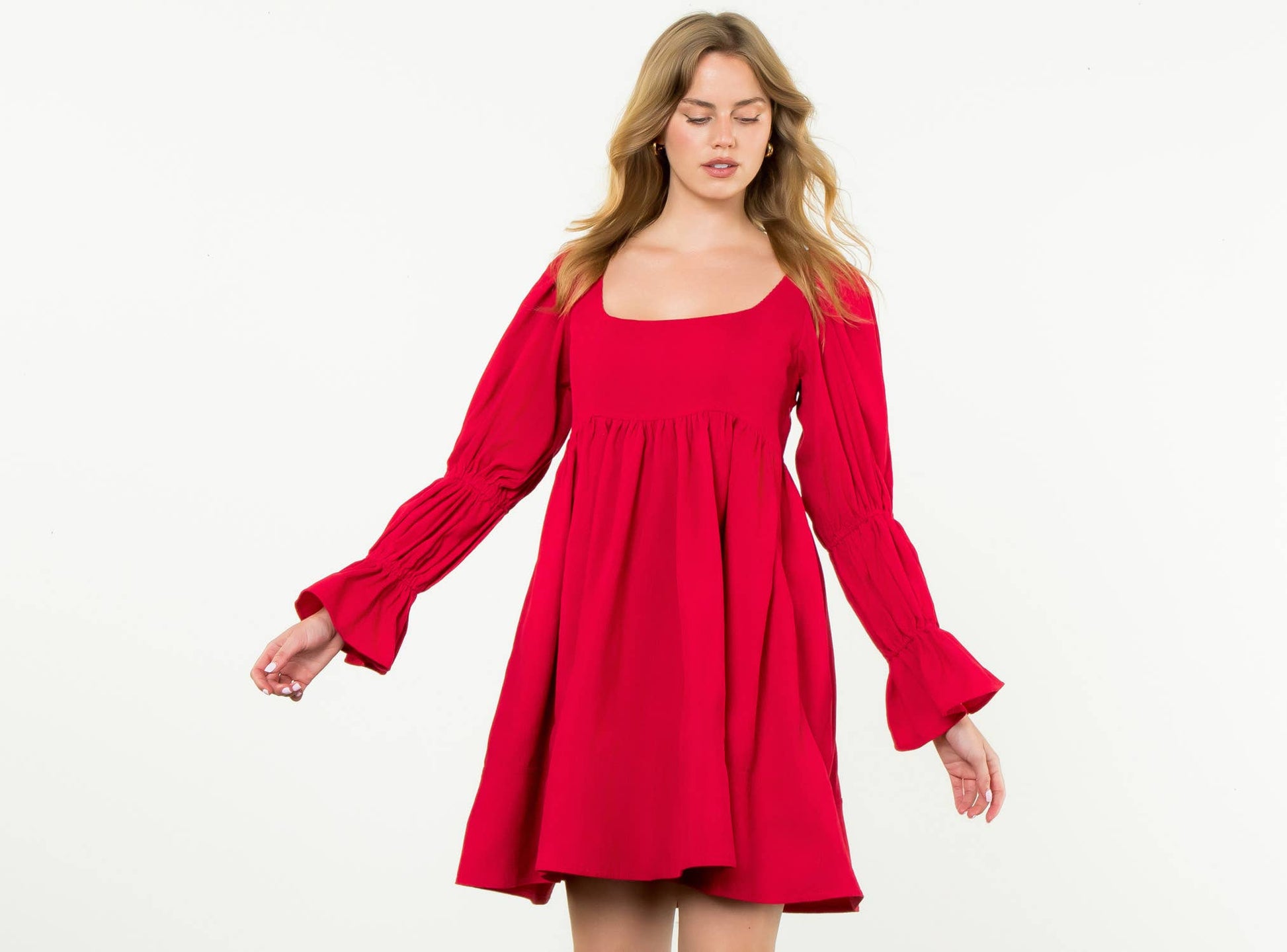 Woman wearing a red dress with long sleeves on a white background