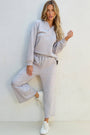 Woman wearing a light gray tracksuit against a white background