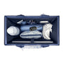 Top-down view of a navy blue organizer bag packed with travel accessories, including a patterned pouch, a water bottle, a car key fob, and a plastic bag, on a white background.