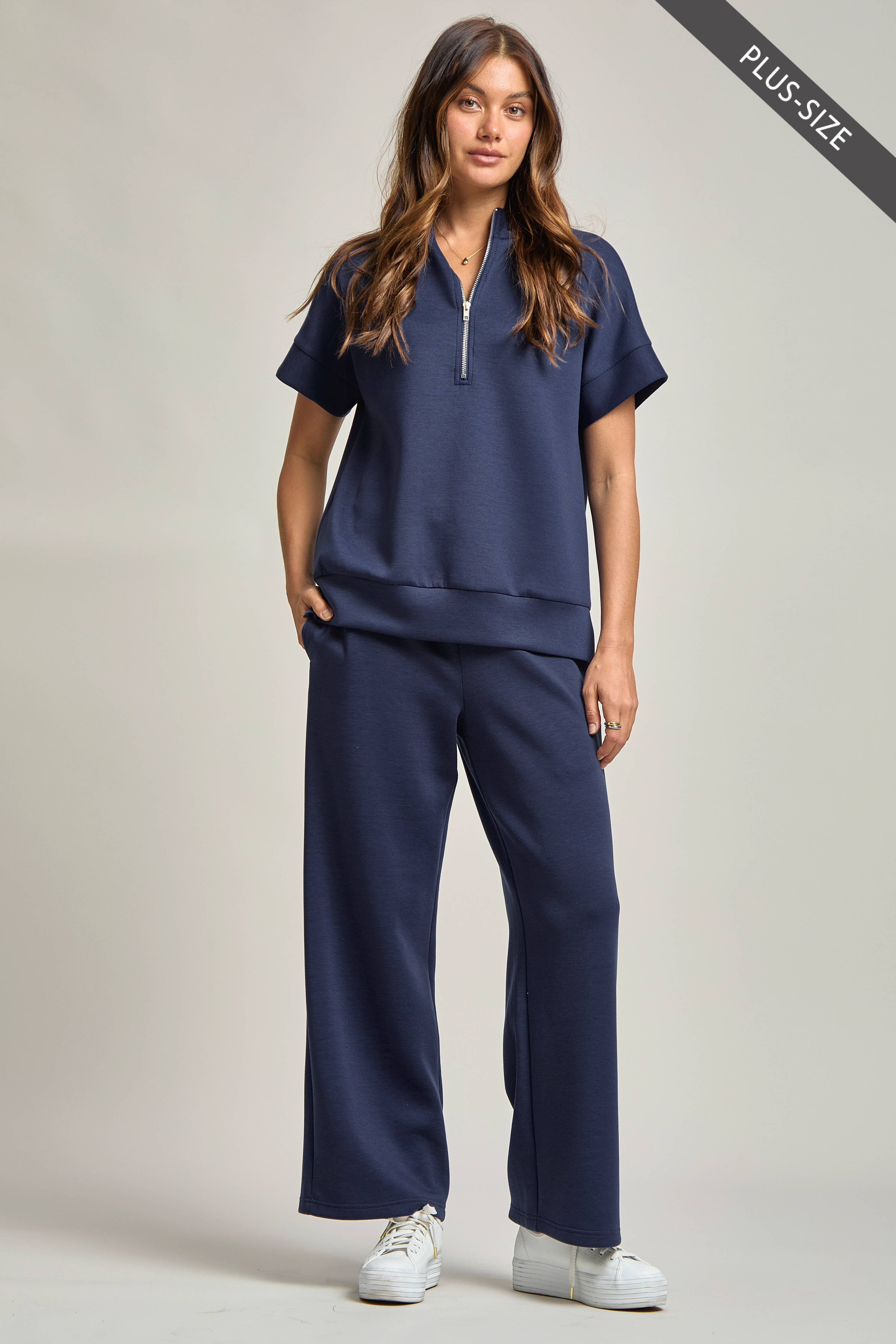 Woman wearing a navy blue scrub set on a plain background