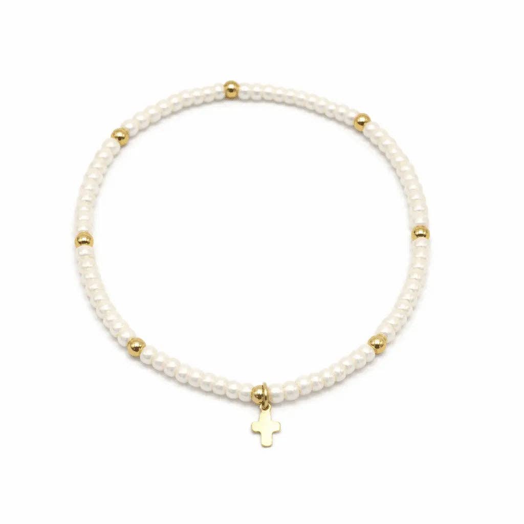 White beaded bracelet with gold accents and a cross charm on a white background