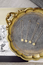 Gold necklaces on a decorative tray with a vintage-style background