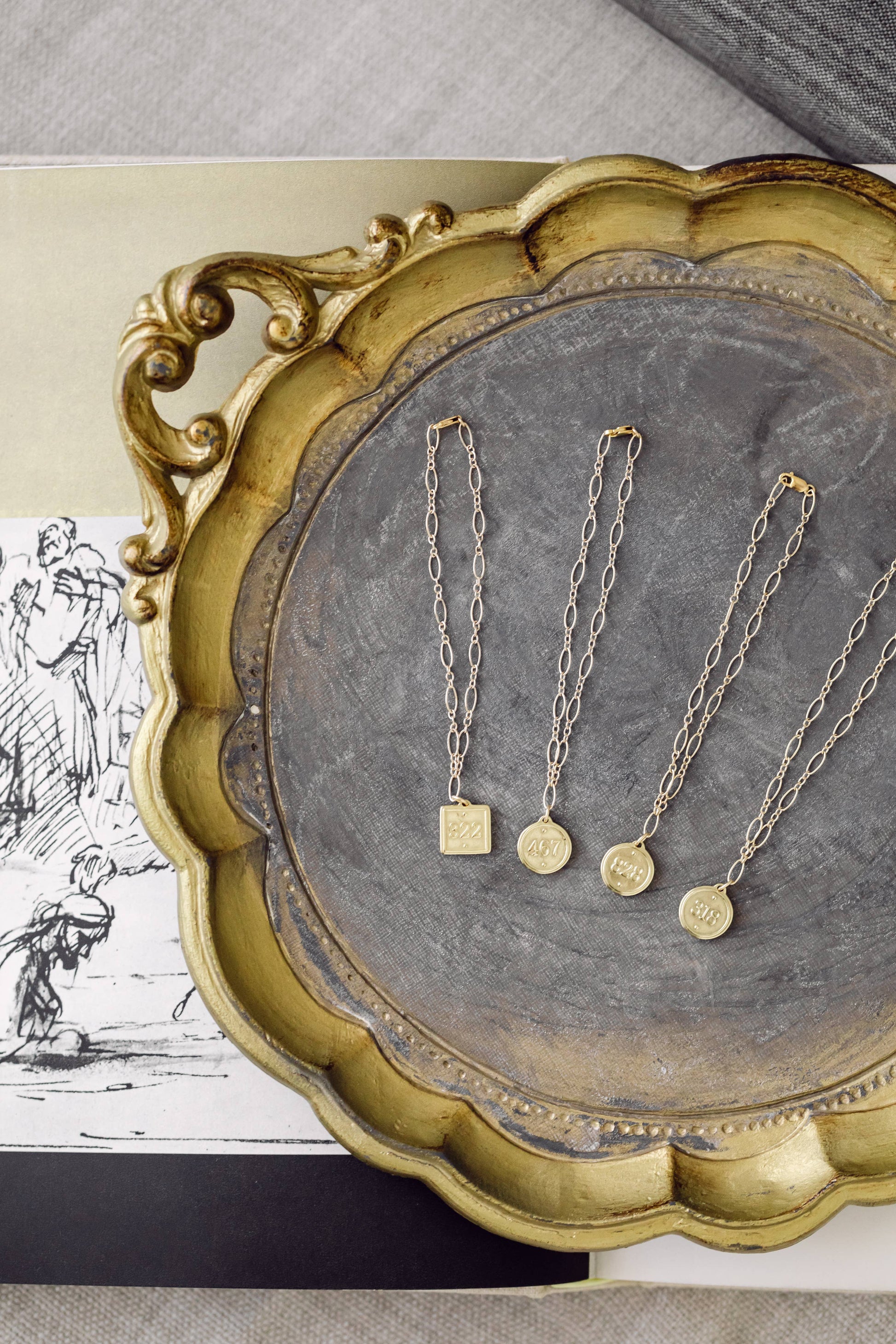 Gold necklaces on a decorative tray with a vintage-style background