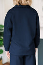 Person wearing a navy textured shirt and pants in an indoor setting