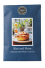 A blue scented candle packet from the brand House of Match Candle Company, featuring a photo of a cinnamon roll on the front and the scent name 'Rise and Shine'.