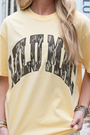 Person wearing a yellow t-shirt with text, standing outdoors.