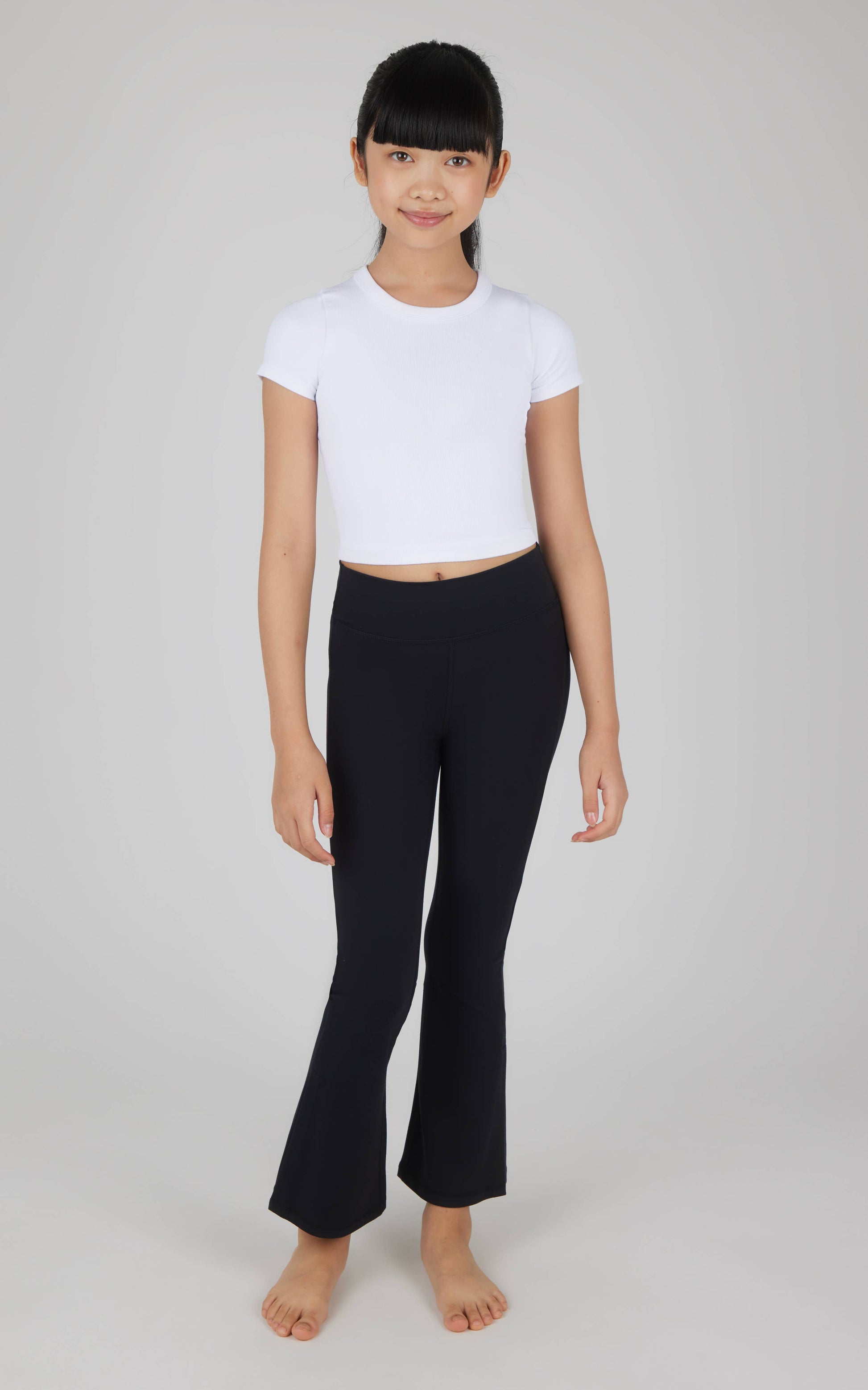 Person wearing a white t-shirt and black pants on a plain background