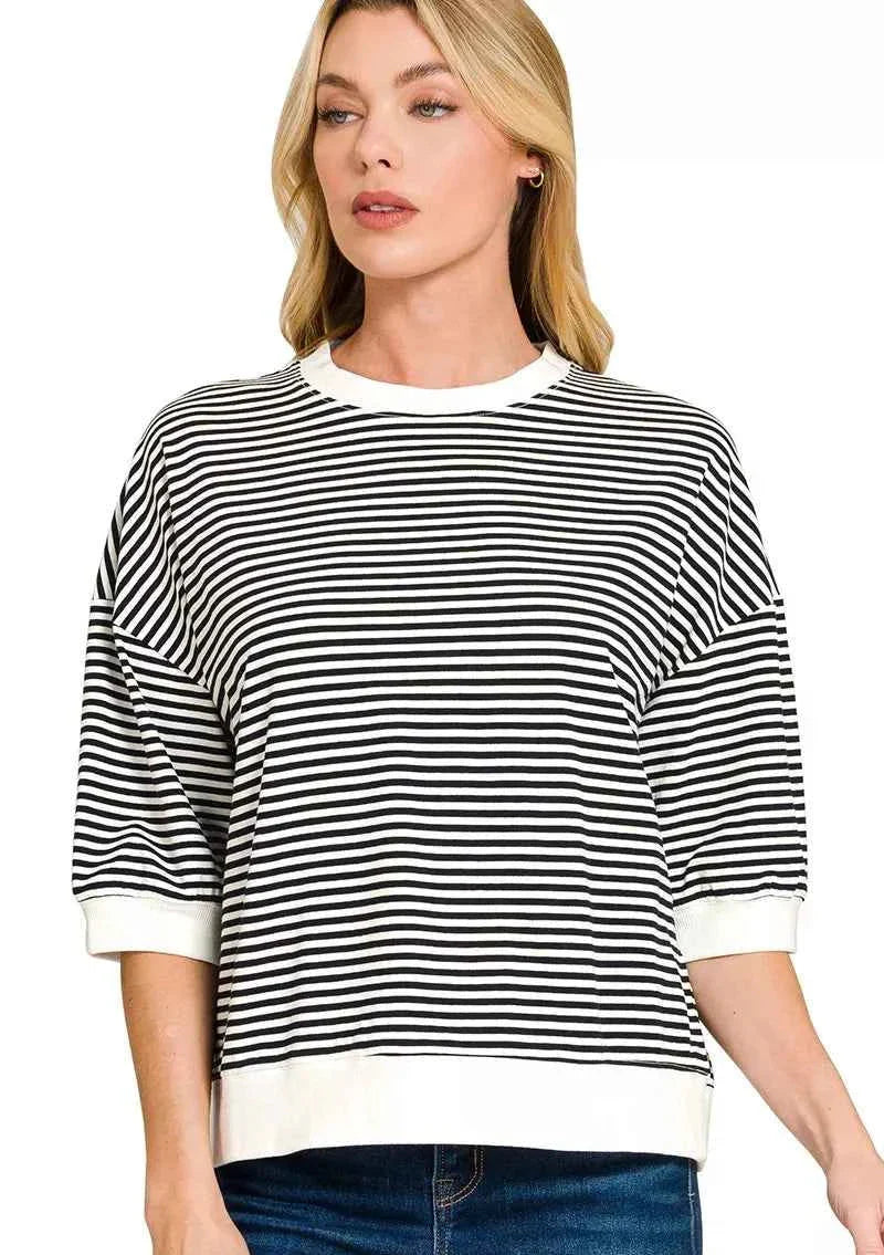 Woman wearing a black and white striped sweater with a plain background
