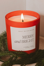 Candle with 'Merry and Bright' label surrounded by greenery