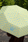 Yellow umbrella with blue polka dots held by a person outdoors