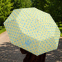 Yellow umbrella with blue polka dots held by a person outdoors