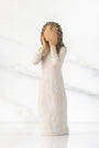 Decorative figurine of a woman with braided hair and a white dress on a marble background
