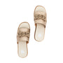 A pair of beige slide sandals with wide straps featuring a braided chain detail, shown from a top-down view on a white background.