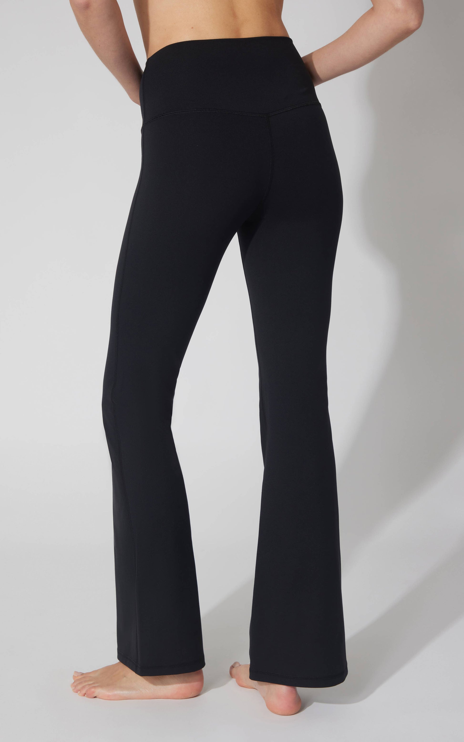 Person wearing black yoga pants on a plain background