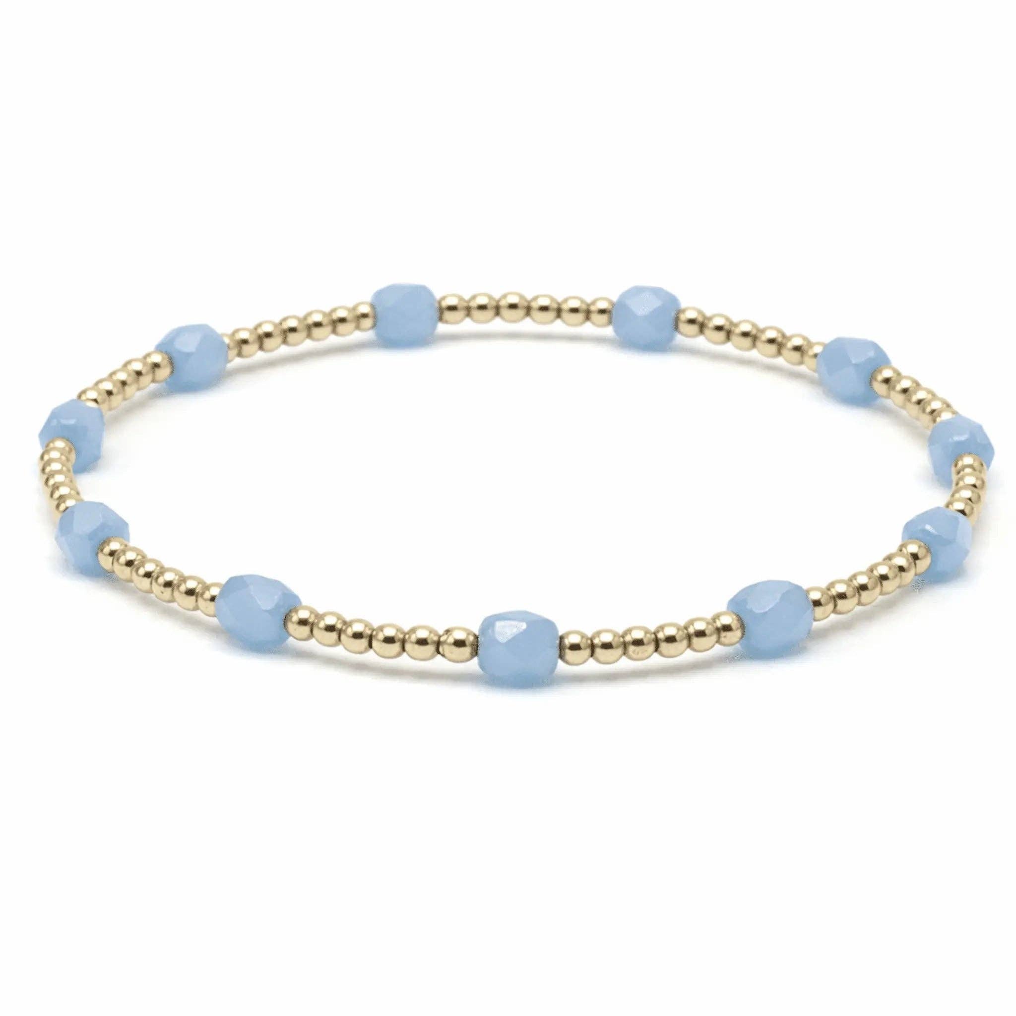 Bracelet with gold beads and light blue stones on a white background