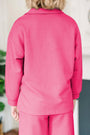 Person wearing a pink textured outfit indoors with a neutral background