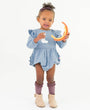 Child wearing a blue dress holding a toy on a white background