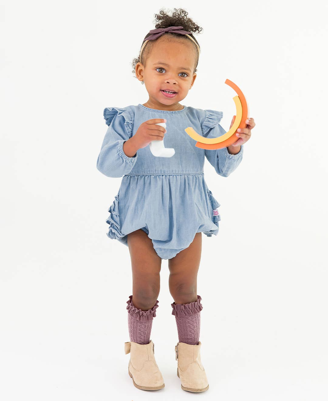 Child wearing a blue dress holding a toy on a white background