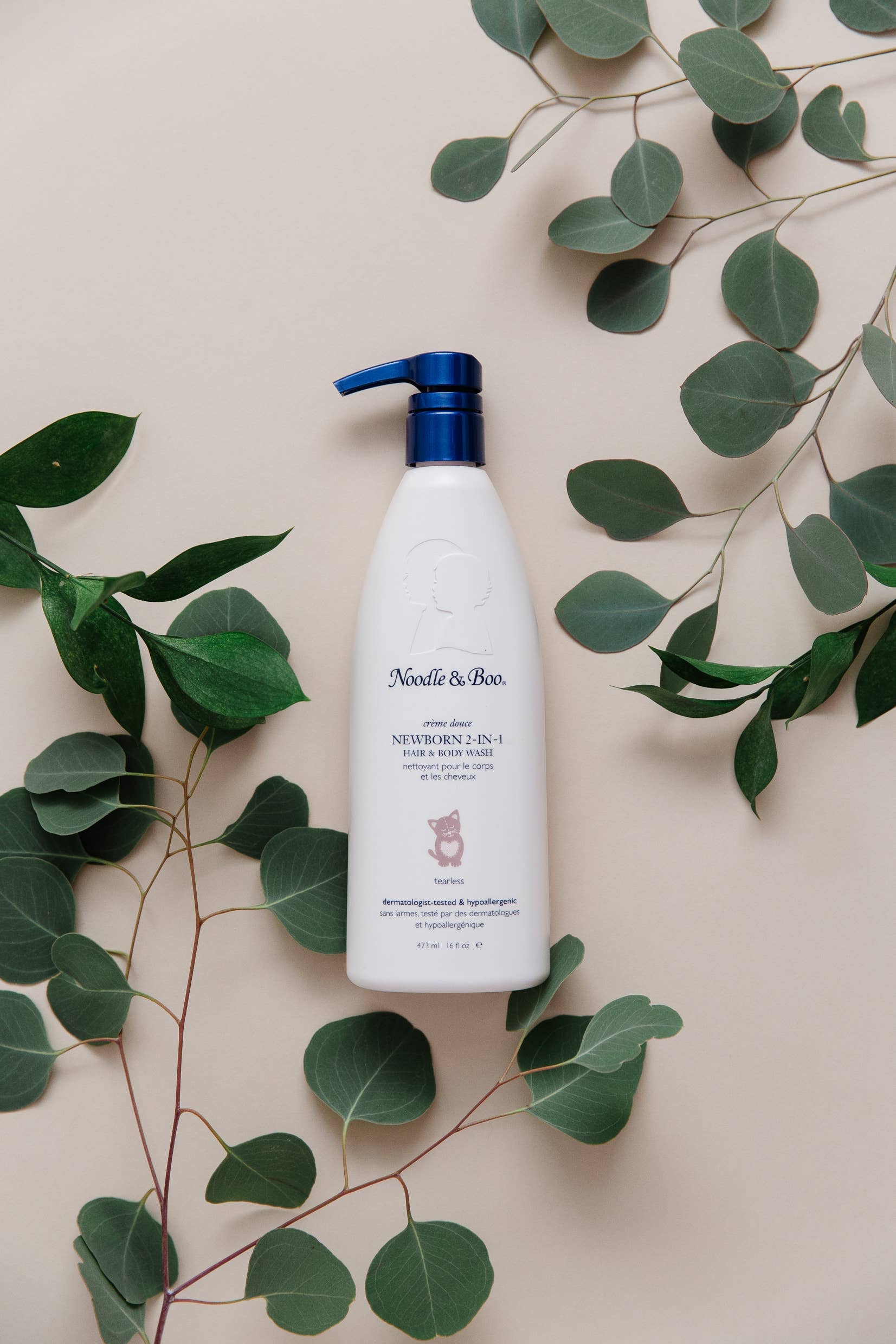 Noodle & Boo bottle on a beige background with green leaves