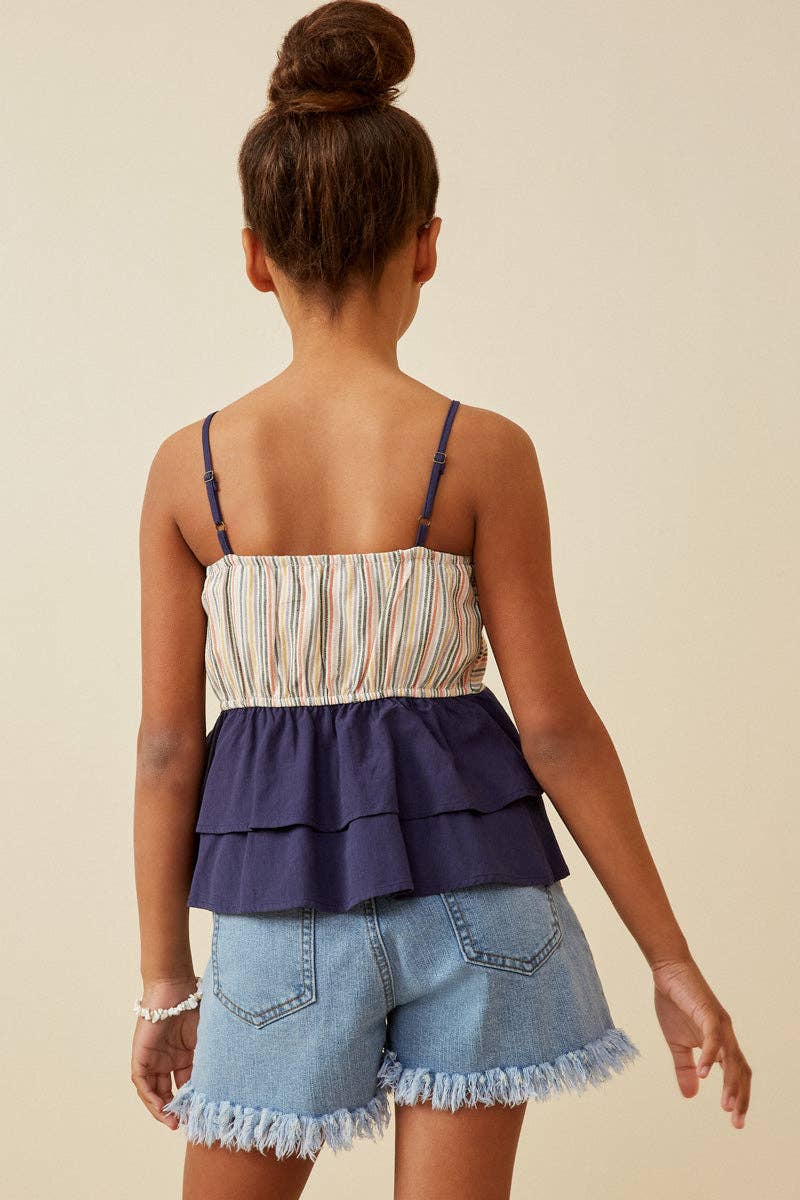 Back view of a person wearing a layered top and denim shorts on a beige background
