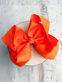 Large orange bow on a white plate against a light wooden background