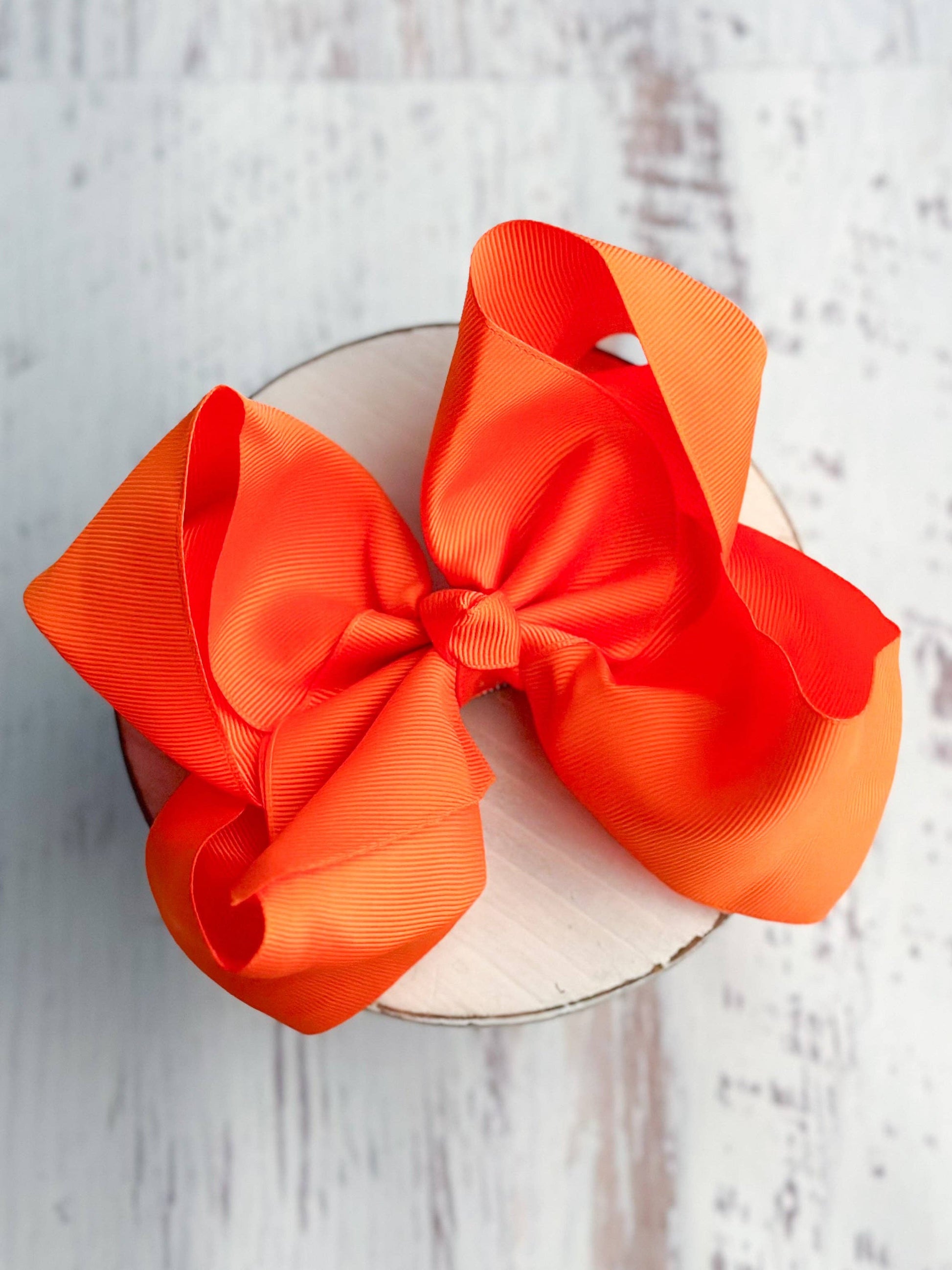 Large orange bow on a white plate against a light wooden background