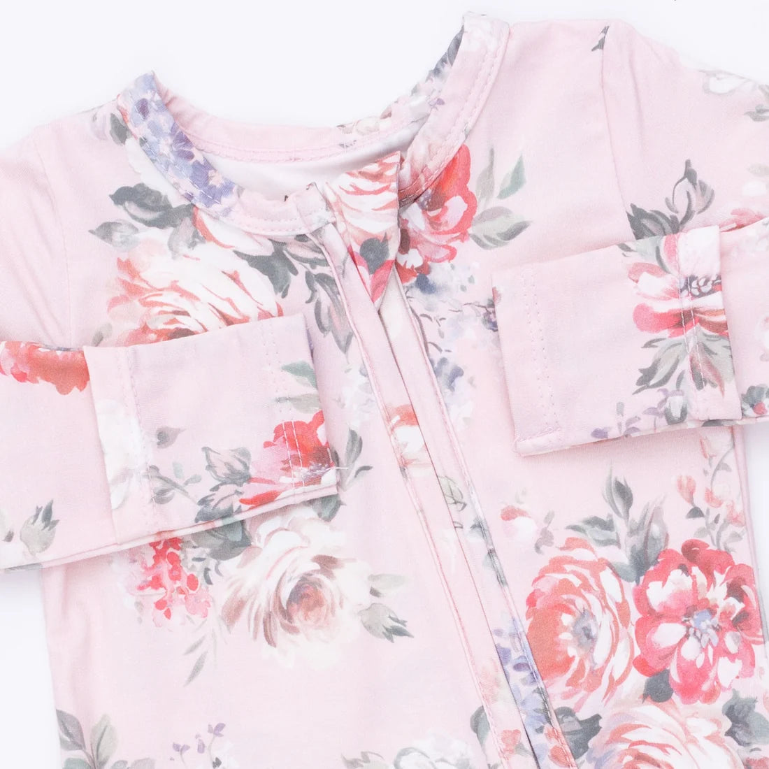 A close-up of a baby long-sleeve top in light pink with a watercolor floral print featuring red, white, and purple flowers with green leaves.